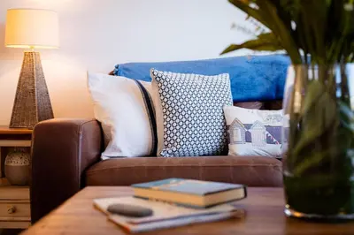 a living room with a couch with pillows and a table at Seaspray in Port Isaac
