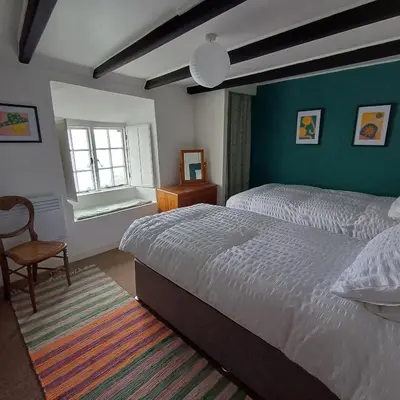 a bedroom with a bed and a chair and a window at The Old Post Office in Coverack