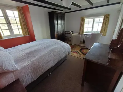 a bedroom with a bed and a desk and windows at The Old Post Office in Coverack