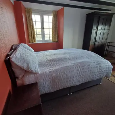 a bedroom with a bed with red walls and a window at The Old Post Office in Coverack
