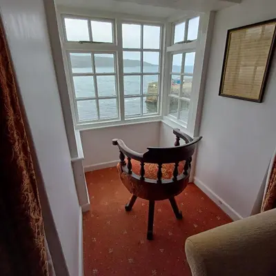 a room with a chair in front of a window at The Old Post Office in Coverack
