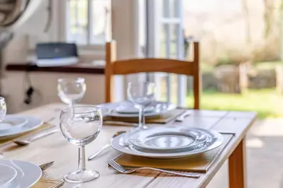 a wooden table with plates and wine glasses on it at 2 Bed in Duloe oc-f31903 in Duloe
