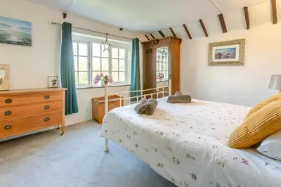 a bedroom with a bed and a dresser and windows at 2 Bed in Duloe oc-f31903 in Duloe