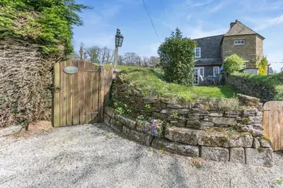 a stone fence with a wooden gate in front of a house at 2 Bed in Duloe oc-f31903 in Duloe