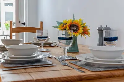 a table with plates and glasses and a vase with a sunflower at 2 Bed in Pensilva oc-z31812 in Middlehill