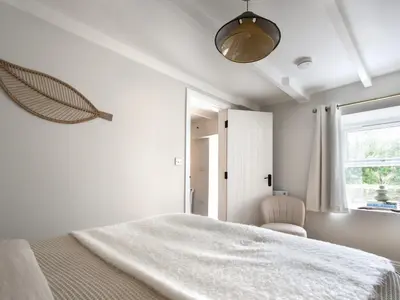 a white bedroom with a large bed and a window at Rock View in St Austell