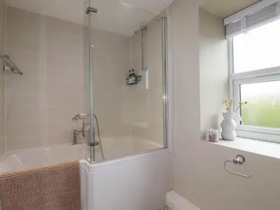 a bathroom with a tub and a shower with a glass door at Rock View in St Austell