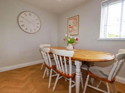 a dining room with a wooden table and a clock on the wall at Rock View in St Austell