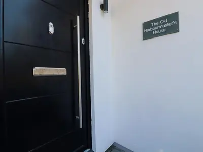 a black door with a sign on a wall at The Old Harbour Masters House in Fowey