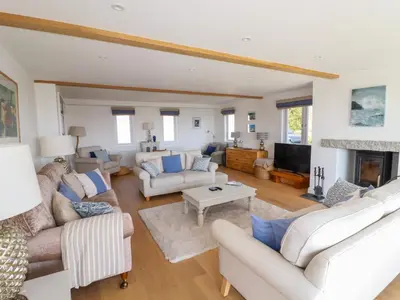 a living room with white furniture and a fireplace at The Old Harbour Masters House in Fowey