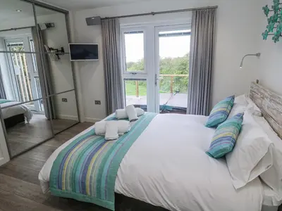 a bedroom with a large bed with a large window at Petroc in Redruth