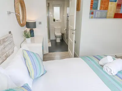 a bedroom with a white bed and a bathroom at Petroc in Redruth