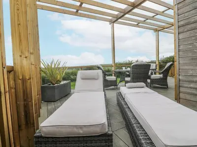 a patio with two beds and a table and chairs at Petroc in Redruth