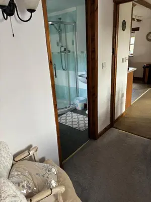 a glass door leading to a bathroom with a shower at Tregatherall Barn in Boscastle