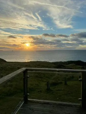 a sunset over the ocean from a wooden deck at Seaview Caravan, Perran Sands in Perranporth