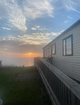 a house with the sunset in the background at Seaview Caravan, Perran Sands in Perranporth