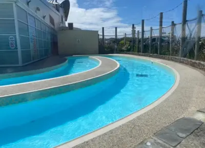 a swimming pool with blue water in front of a building at Seaview Caravan, Perran Sands in Perranporth