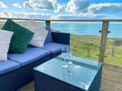 a couch and two wine glasses on a table at Seaview Caravan, Perran Sands in Perranporth