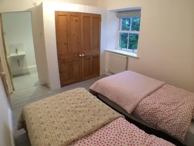 a bedroom with two twin beds and a window at Little Nampara Cottage in Portreath