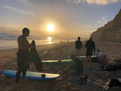a group of surfers on the beach at sunset at Little Nampara Cottage in Portreath