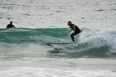 a man riding a wave on a surfboard in the ocean at Little Nampara Cottage in Portreath