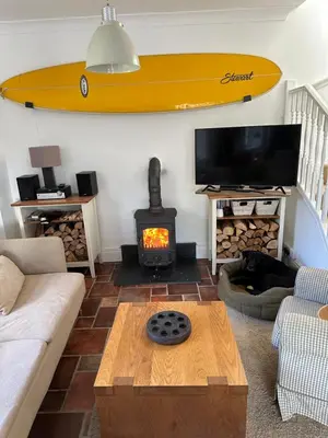 a living room with a surfboard hanging on the wall at Little Nampara Cottage in Portreath