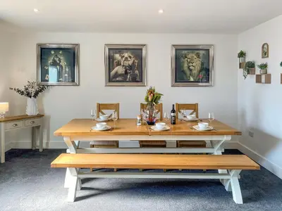 a dining room with a table and some pictures on the wall at The Pines in Redruth