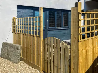 a wooden fence in front of a blue house at The Pines in Redruth