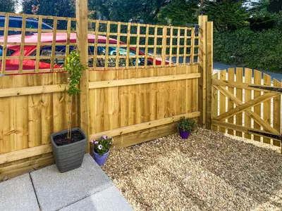 a wooden fence with potted plants in front of a car at The Pines in Redruth