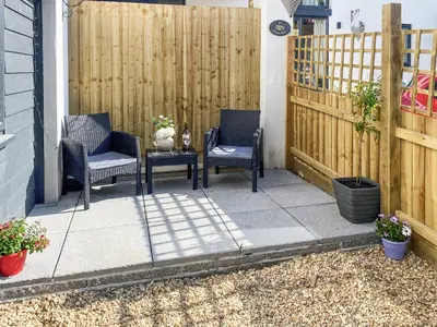 a patio with two chairs and a table and a fence at The Pines in Redruth