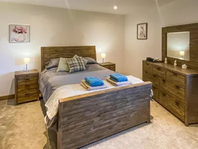 a bedroom with a bed with two dressers and a mirror at The Pines in Redruth