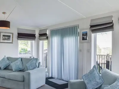 a living room with a couch and some windows at Sunshine Lodge in Polperro