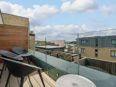 a balcony with chairs and a view of buildings at Ebbtide in Newquay
