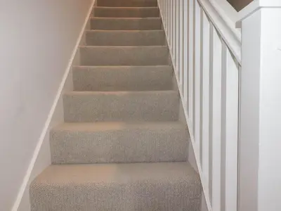 a staircase with gray carpet and white railings at Ebbtide in Newquay