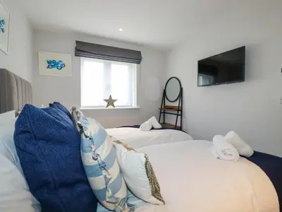 a room with two beds and a tv and a window at Ebbtide in Newquay