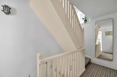 a white staircase in a house with a mirror at Finest Retreats - Garden Cottage in Fowey in Fowey