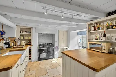 a large kitchen with white cabinets and a stove at Finest Retreats - Garden Cottage in Fowey in Fowey
