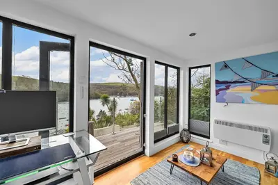 a living room with large windows and a flat screen tv at Finest Retreats - Garden Cottage in Fowey in Fowey