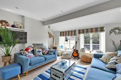 a living room with blue couches and a tv at Finest Retreats - Garden Cottage in Fowey in Fowey