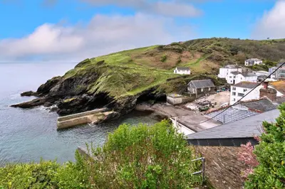 a group of houses on a hill next to the water at Finest Retreats - The Old Store in Portloe