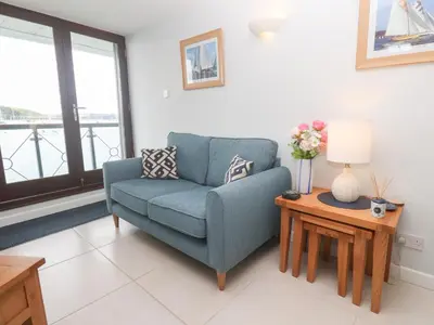 a living room with a blue chair and a table at Tobys Quay in Falmouth