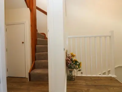 a hallway with a vase of flowers and stairs at Breakers Point in St Ives
