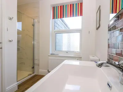 a bathroom with a tub and a shower and a window at Breakers Point in St Ives