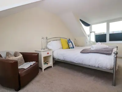a bedroom with a bed and a chair at Breakers Point in St Ives