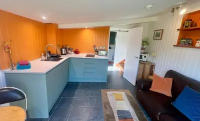 a kitchen with orange walls and a couch in a room at The Escape in Crackington Haven