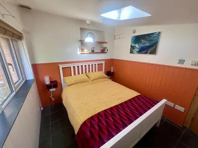 a bedroom with a bed with an orange wall at The Escape in Crackington Haven