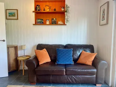 a brown leather couch with orange and blue pillows at The Escape in Crackington Haven