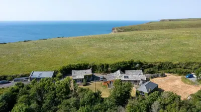 an aerial view of a house on a hill next to the ocean at The Escape in Crackington Haven