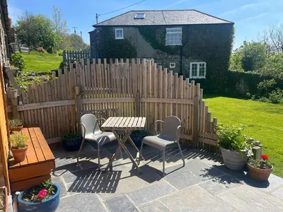 a patio with a table and chairs and a fence at The Escape in Crackington Haven