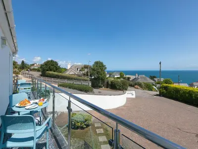a balcony with a table and chairs and the ocean at Skysail in St Ives